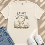 A white t-shirt with a whimsical illustration of a rabbit gazing through a telescope, accompanied by the text "LEAVE ROOM FOR WONDER".