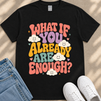 A black t-shirt with a colorful graphic design featuring the text "What If You Already Are Enough?" surrounded by smiling clouds.