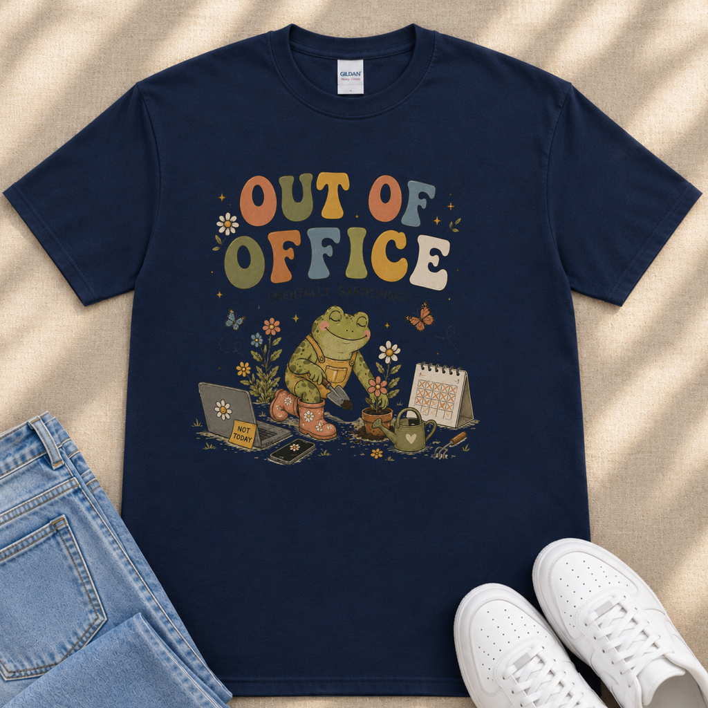 A navy blue t-shirt with a colorful graphic design depicting a frog sitting on a laptop, surrounded by various office-related items such as a calendar, a phone, and a coffee mug.