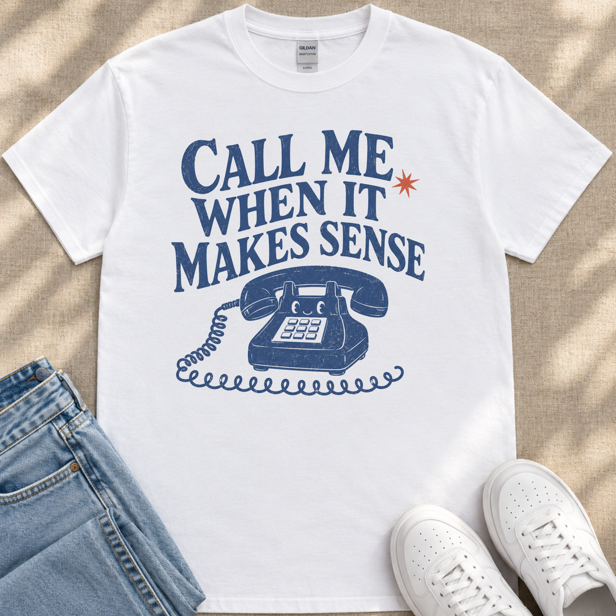 A white t-shirt with a graphic design that says "Call me when it makes sense" and features a telephone with a star above it.