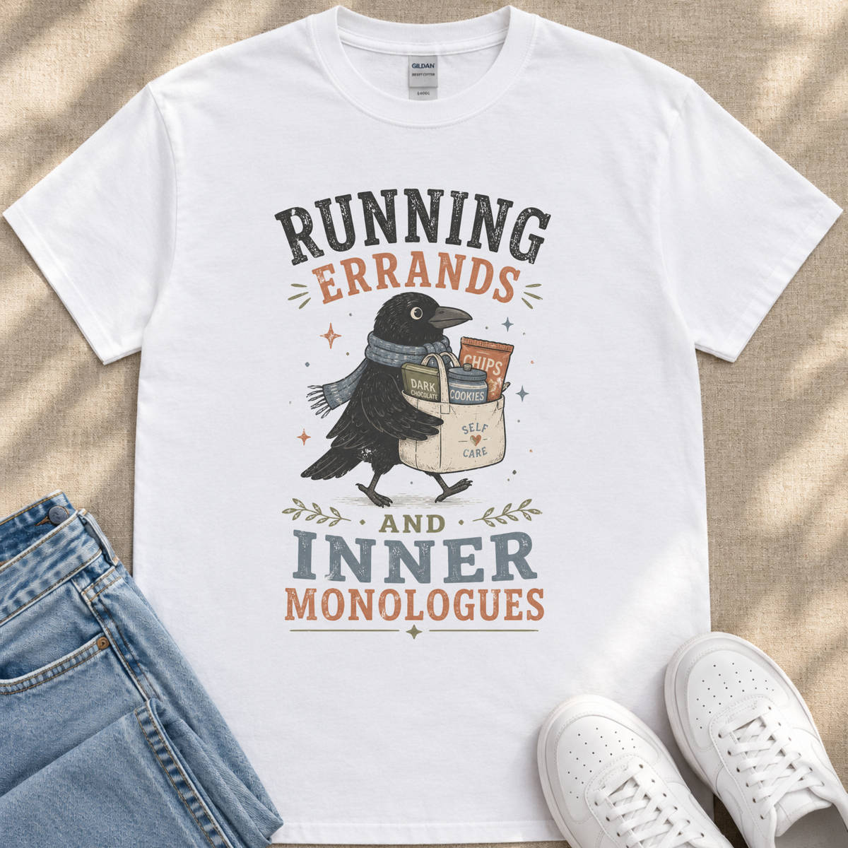 A white t-shirt with a graphic design featuring a black bird carrying a bag with the text "RUNNING errands AND INNER MONOLOGUES" printed on it.