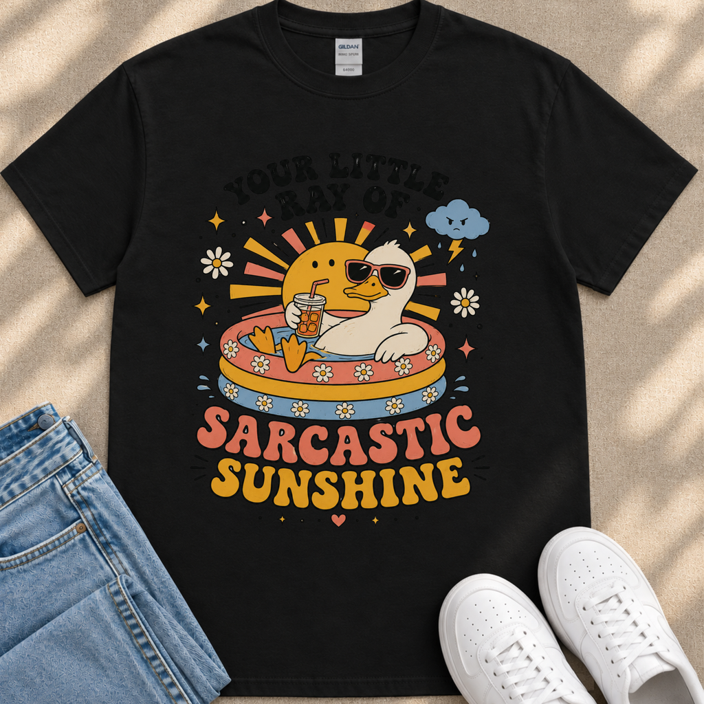 A black t-shirt with a colorful graphic design depicting a duck wearing sunglasses and sitting in a pool, surrounded by sun and clouds, along with the text "Your little ray of SARCASTIC SUNSHINE".