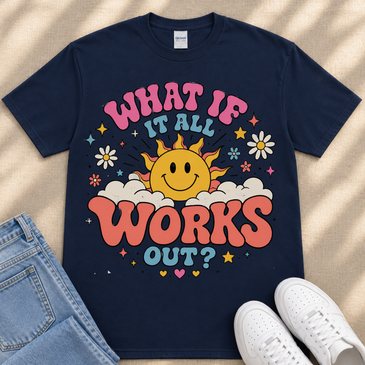 A navy blue t-shirt with a colorful graphic design featuring a smiling sun and the text "What If It All Works Out?"