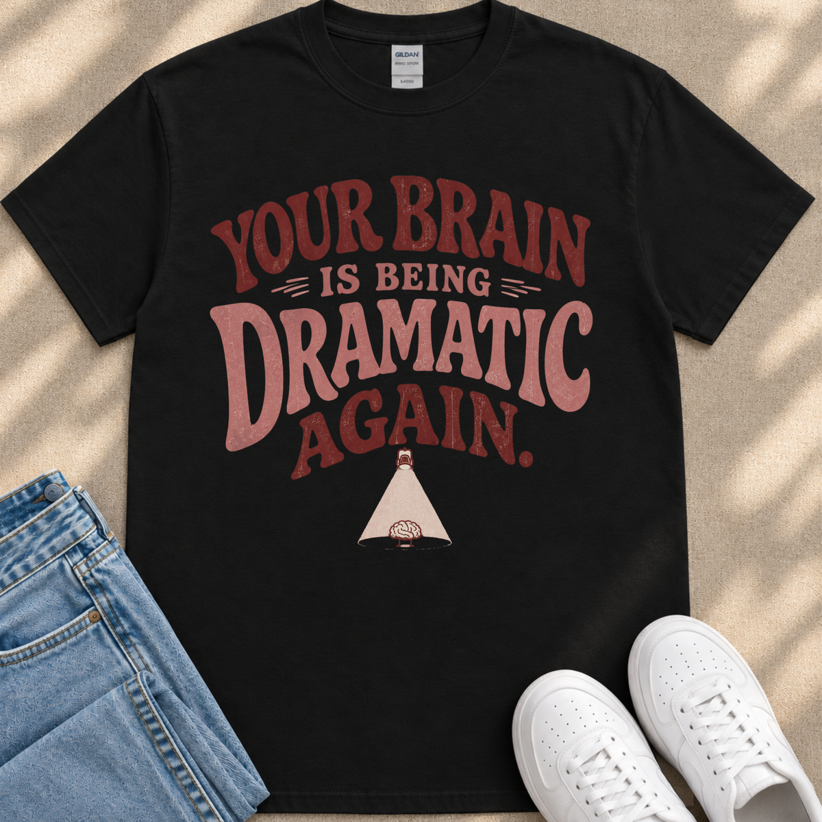 A black t-shirt with a humorous text printed on it, along with a pair of jeans and white sneakers.
