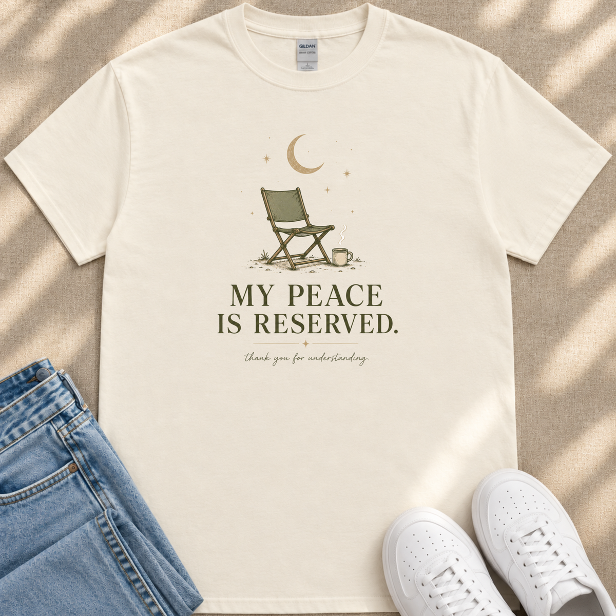 A white t-shirt with a graphic design and text printed on it, along with a pair of jeans and white sneakers.