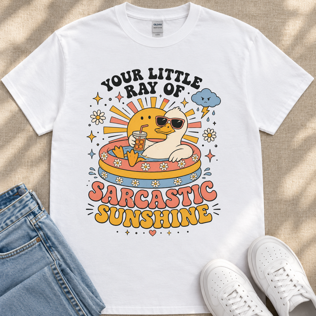 A white t-shirt with a colorful graphic design depicting a duck wearing sunglasses and holding a drink, surrounded by sun-like elements and text that reads "Your little ray of sarcastic sunshine".