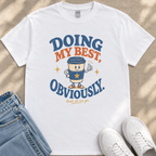 A white t-shirt with a graphic design featuring a coffee cup character and the text "Doing my best, Obviously. look at me go."