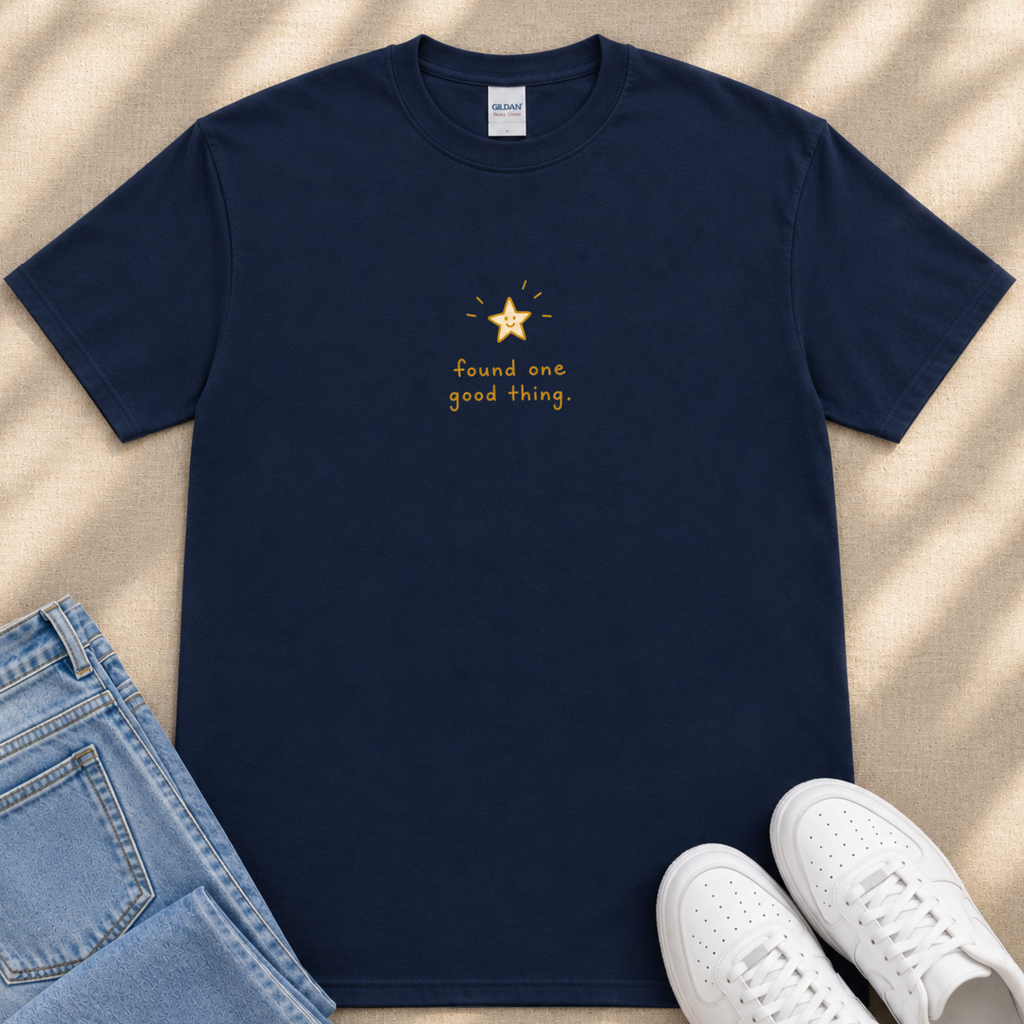 A navy blue t-shirt with a gold star and the text "Found one good thing" printed on it, along with a pair of blue jeans and white sneakers.