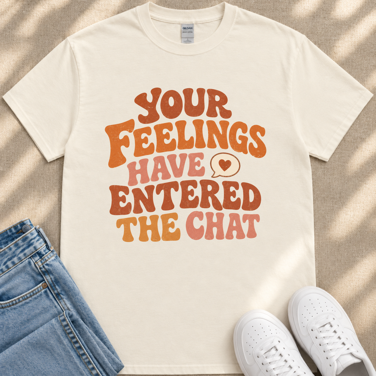 A white t-shirt with a colorful text design that reads "Your Feelings Have Entered The Chat" in a retro style.