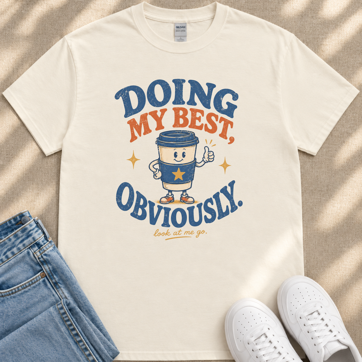 a white t-shirt with a graphic design that includes a coffee cup character and text, along with a pair of jeans and white sneakers.