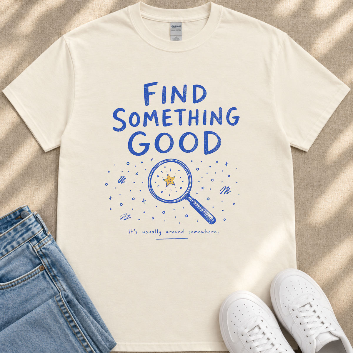 a white t-shirt with a blue graphic design and text, a pair of blue jeans, and a pair of white sneakers.