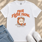 A white t-shirt with a graphic design featuring a cartoon alarm clock and the text "not right now. maybe later."