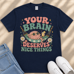 A navy blue t-shirt with a colorful graphic design that says "YOUR BRAIN DESERVES NICE THINGS" and features a cartoon brain in a hammock.