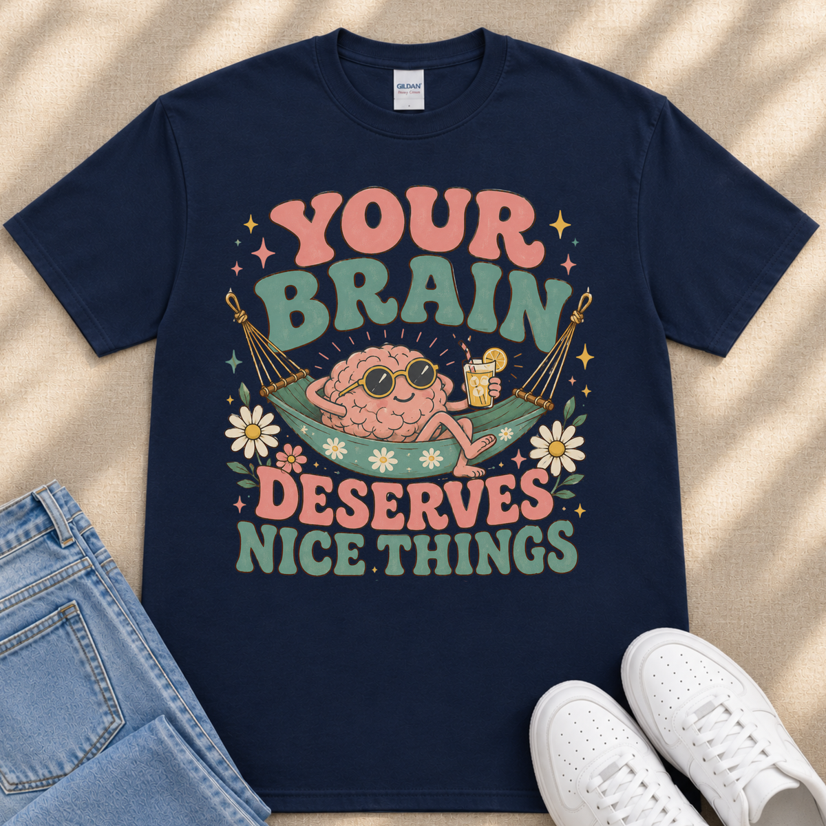 A navy blue t-shirt with a colorful graphic design that says "YOUR BRAIN DESERVES NICE THINGS" and features a cartoon brain in a hammock.