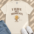 A white t-shirt with a lightbulb graphic and text, along with a pair of jeans and white sneakers, laid out on a beige surface.