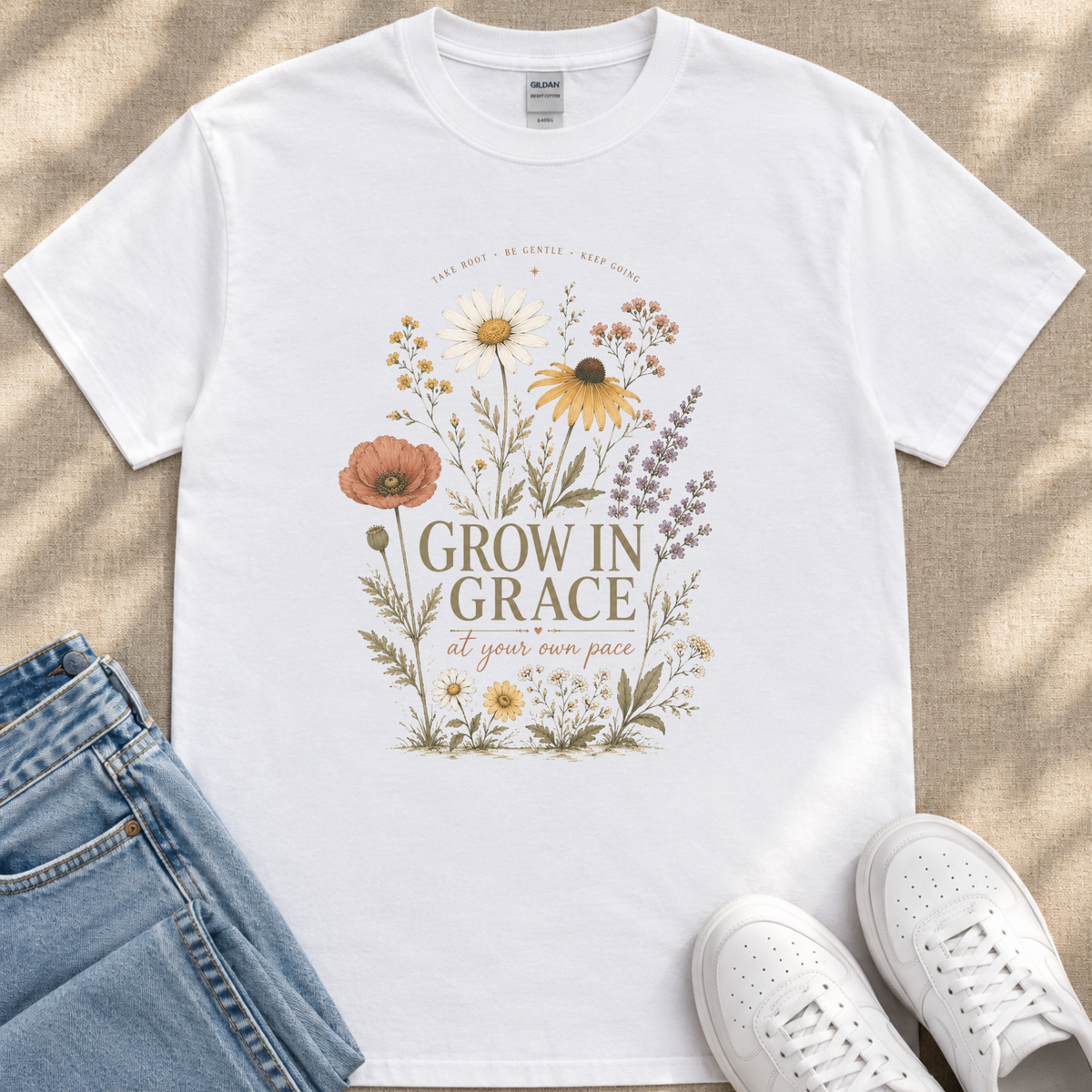 A white t-shirt with a floral design and the text "Grow in Grace" printed on it, along with a pair of jeans and white sneakers.