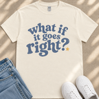 A white t-shirt with a blue text design that reads "What if it goes right?" along with a yellow star, placed on a beige surface next to a pair of blue jeans and white sneakers.