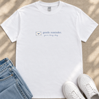 A white t-shirt with a blue envelope icon and the text "gentle reminder. you're doing great" printed on it, along with a pair of blue jeans and white sneakers.