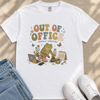 A white t-shirt with a colorful graphic design depicting a frog holding a laptop and surrounded by gardening-related items, along with the text "Out of Office (Mentally Gardening)" and various other elements.