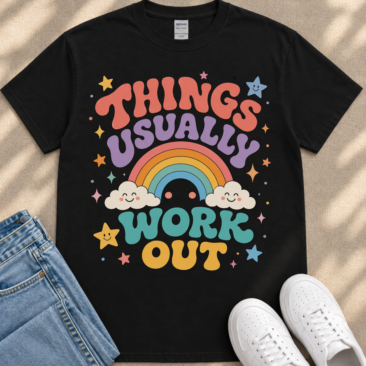 A black t-shirt with a colorful graphic design that says "THINGS USUALLY WORK OUT" along with a rainbow, clouds, stars, and a smiley face.