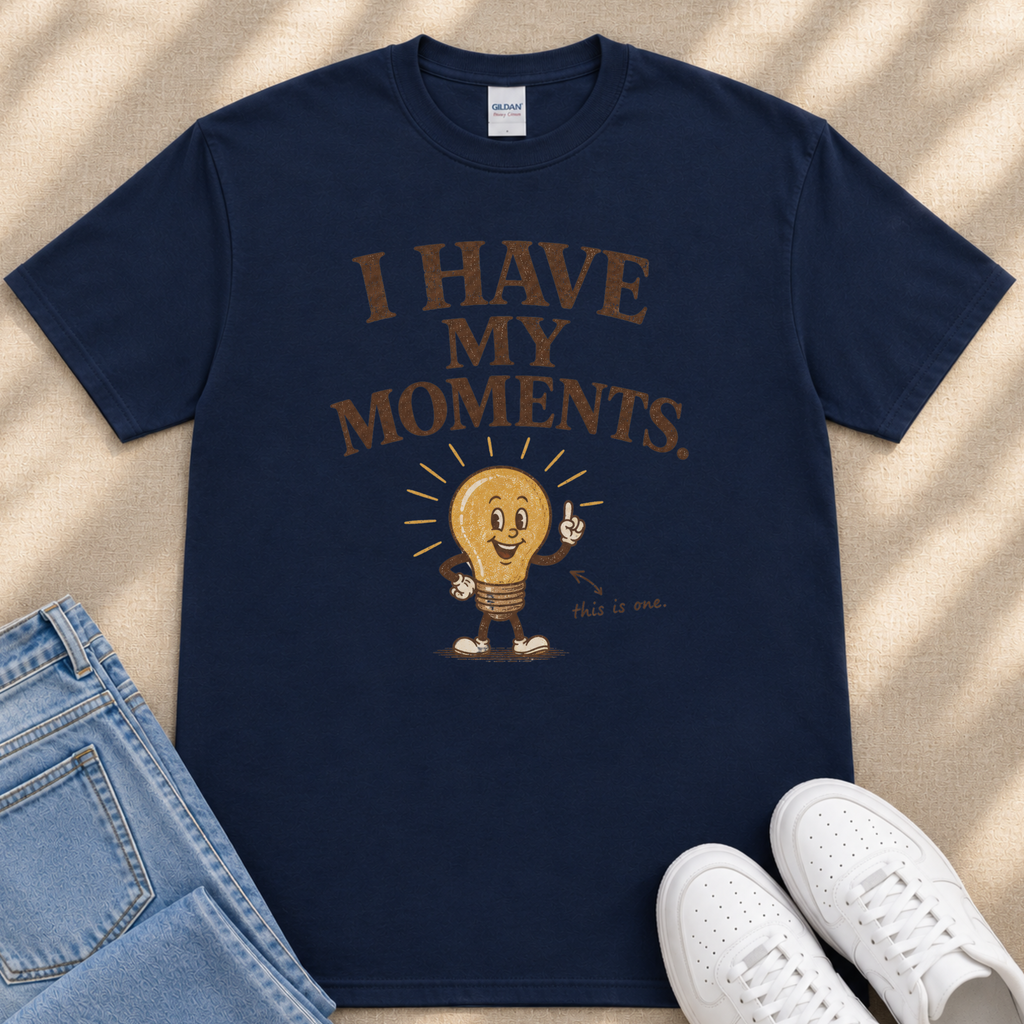 A navy blue t-shirt with a graphic design of a light bulb character and the text "I HAVE MY MOMENTS" printed on it.