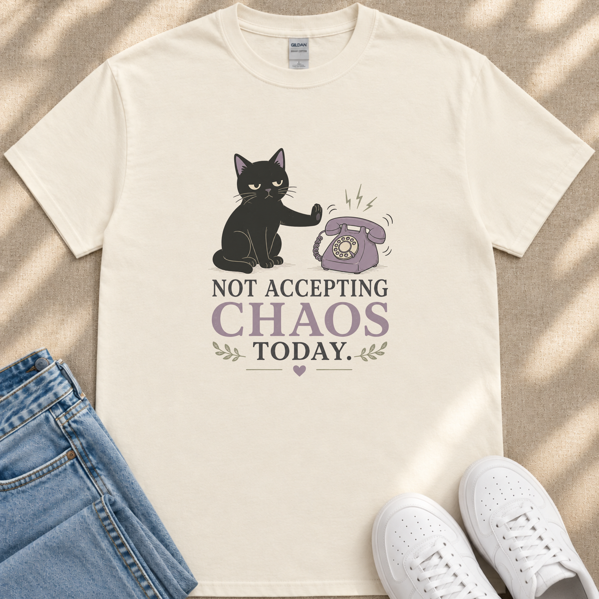 A white t-shirt with a graphic design depicting a black cat and a telephone, along with the text "NOT ACCEPTING CHAOS TODAY".