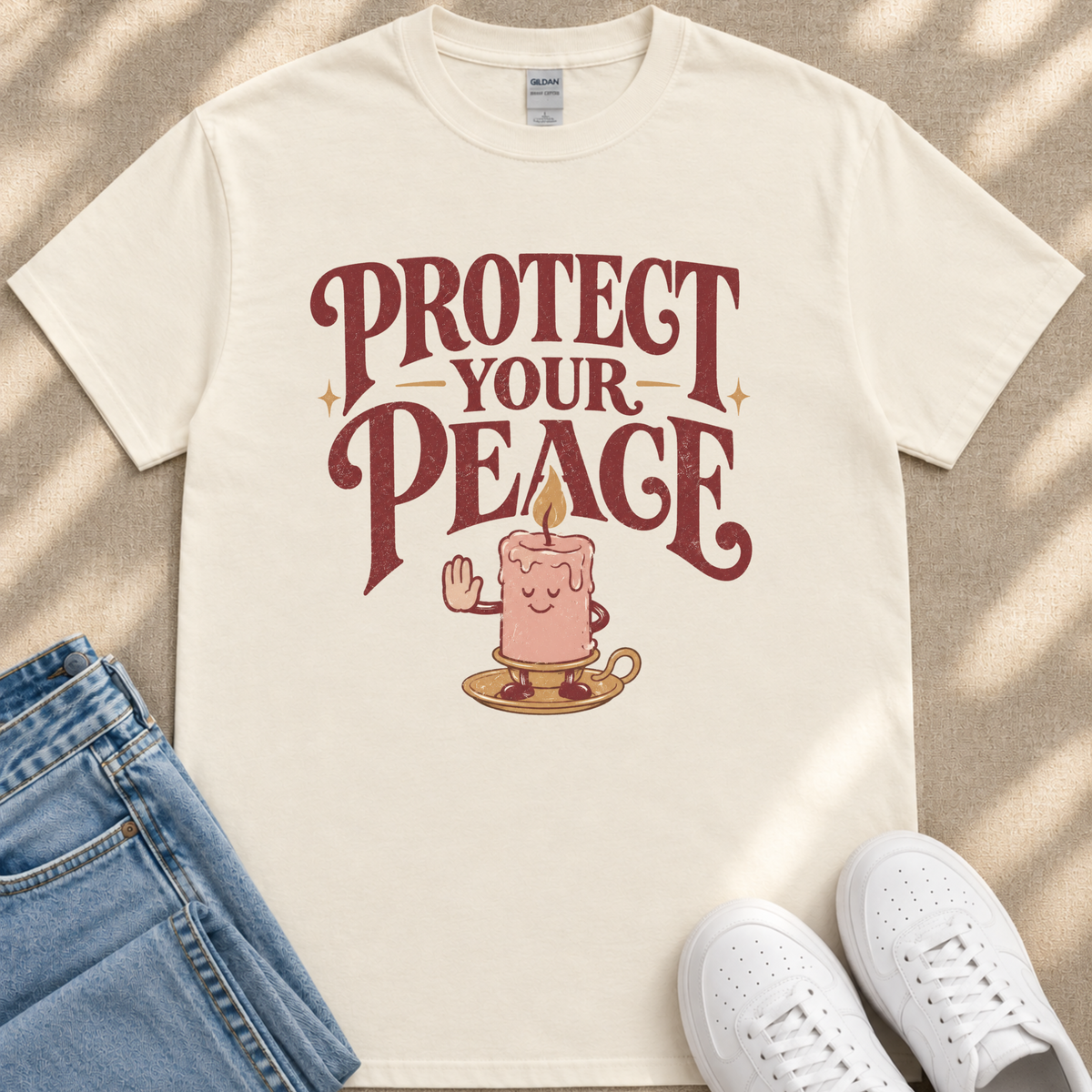 A white t-shirt with a graphic design featuring a candle and the text "PROTECT YOUR PEACE" printed on it.