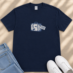 A navy blue t-shirt with a graphic design of a suitcase and a tag that says "Emotional Baggage" is displayed on a beige surface, accompanied by a pair of blue jeans and white sneakers.