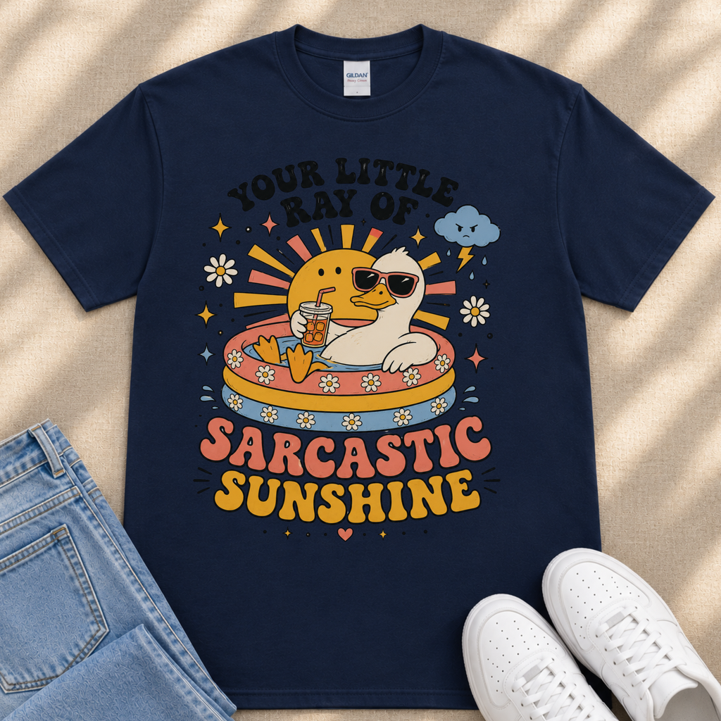 A navy blue t-shirt with a colorful graphic design depicting a duck wearing sunglasses and surrounded by sun-like elements, along with the text "Your little ray of SARCASTIC SUNSHINE".