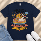 A navy blue t-shirt with a colorful graphic design depicting a duck wearing sunglasses and surrounded by sun-like elements, along with the text "Your little ray of SARCASTIC SUNSHINE".