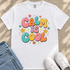 A white t-shirt with a colorful graphic design that says "Calm is cool" surrounded by various decorative elements such as flowers and stars.