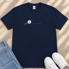 a navy blue t-shirt with a graphic design, a pair of blue jeans, and a pair of white sneakers, all laid out on a beige surface.