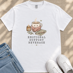 A white t-shirt with a graphic design depicting a cup of coffee, a candle, and a book, along with the text "EMOTIONAL SUPPORT BEVERAGE".