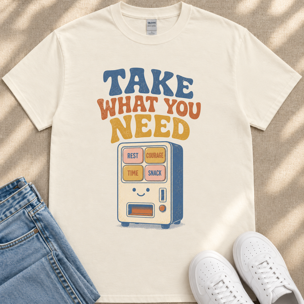 A white t-shirt with a graphic design featuring a vending machine with the text "TAKE WHAT YOU NEED" and a list of items below it.