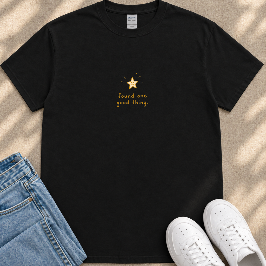 A black t-shirt with a gold star and the text "Found one good thing" printed on it, along with a pair of blue jeans and white sneakers.