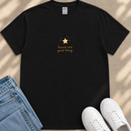 A black t-shirt with a gold star and the text "Found one good thing" printed on it, along with a pair of blue jeans and white sneakers.