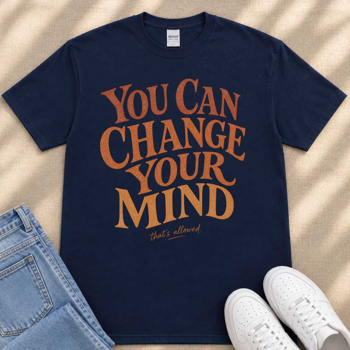 A navy blue t-shirt with the text "You Can Change Your Mind" printed on it, along with a pair of jeans and white sneakers.