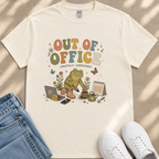A white t-shirt with a colorful graphic design depicting a frog holding a flower, surrounded by various gardening-related items such as a laptop, notebook, and gardening tools.
