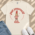 A white t-shirt with a graphic design featuring a lipstick character and the text "put yourself on."