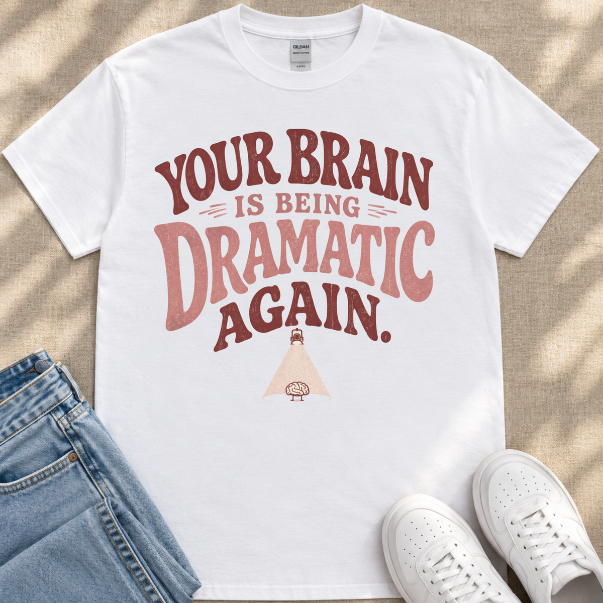 A white t-shirt with a humorous text printed on it, along with a pair of jeans and white sneakers.
