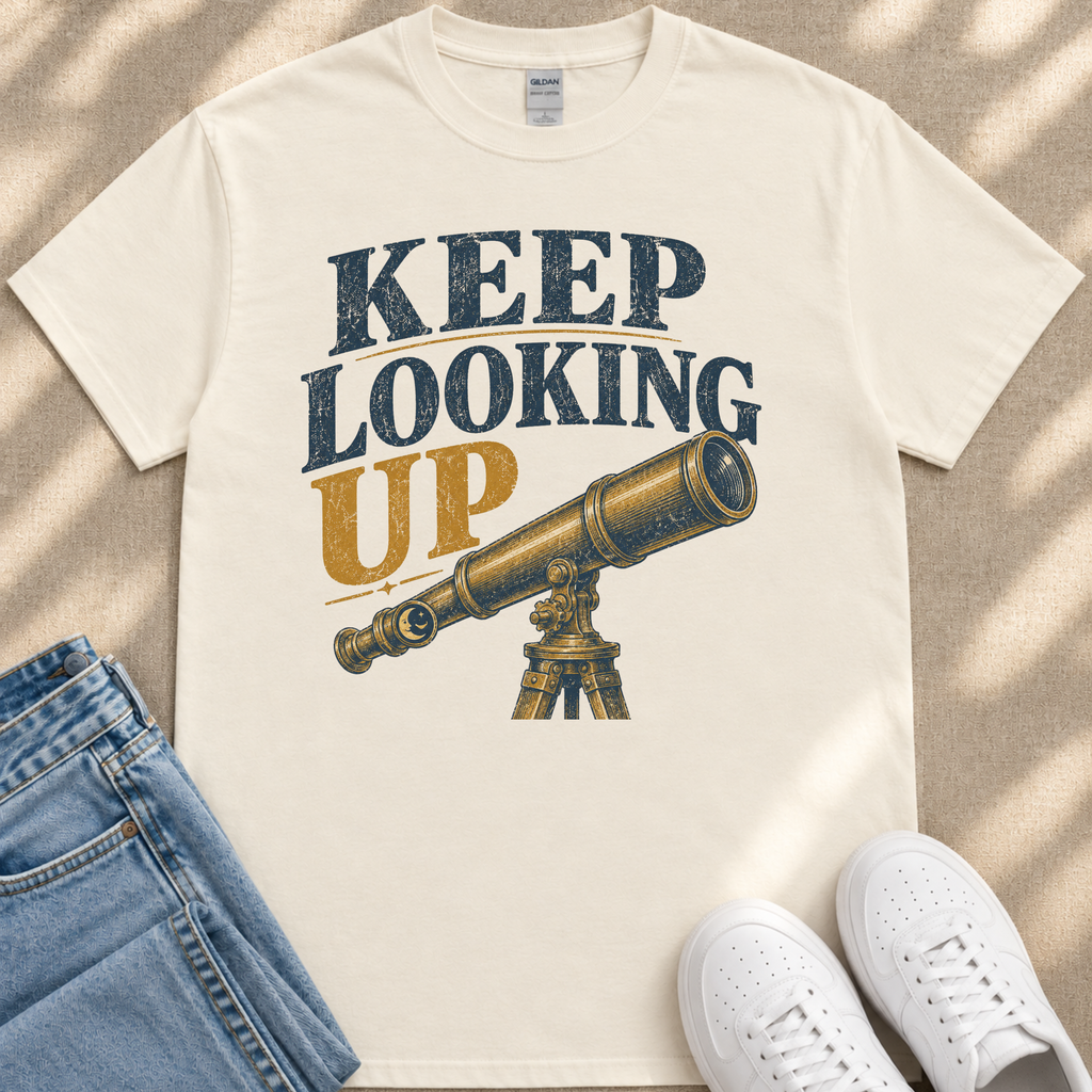 A white t-shirt with a graphic design of a telescope and the text "KEEP LOOKING UP" printed on it, along with a pair of jeans and white sneakers.
