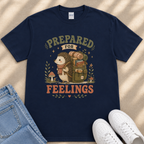 A navy blue t-shirt with a graphic design depicting a hedgehog carrying a backpack and the text "PREPARED FOR FEELINGS" printed on it.