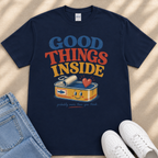 A navy blue t-shirt with a colorful graphic design that says "GOOD THINGS INSIDE" and features a can of tuna with a smiling face.