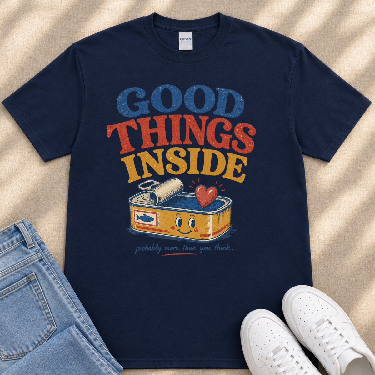 A navy blue t-shirt with a colorful graphic design that says "GOOD THINGS INSIDE" and features a can of tuna with a smiling face.