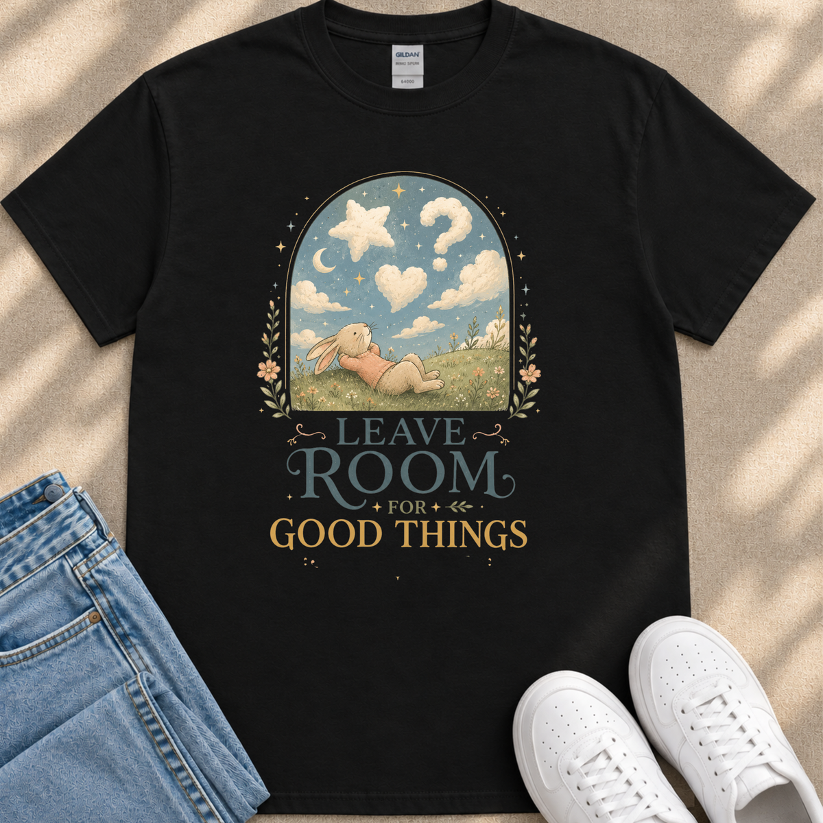A black t-shirt with a whimsical illustration of a rabbit in a field, along with the text "LEAVE ROOM FOR GOOD THINGS" printed on it.