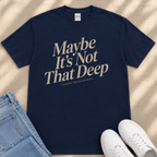 A navy blue t-shirt with the text "Maybe It's Not That Deep" printed on it, along with a pair of jeans and white sneakers.
