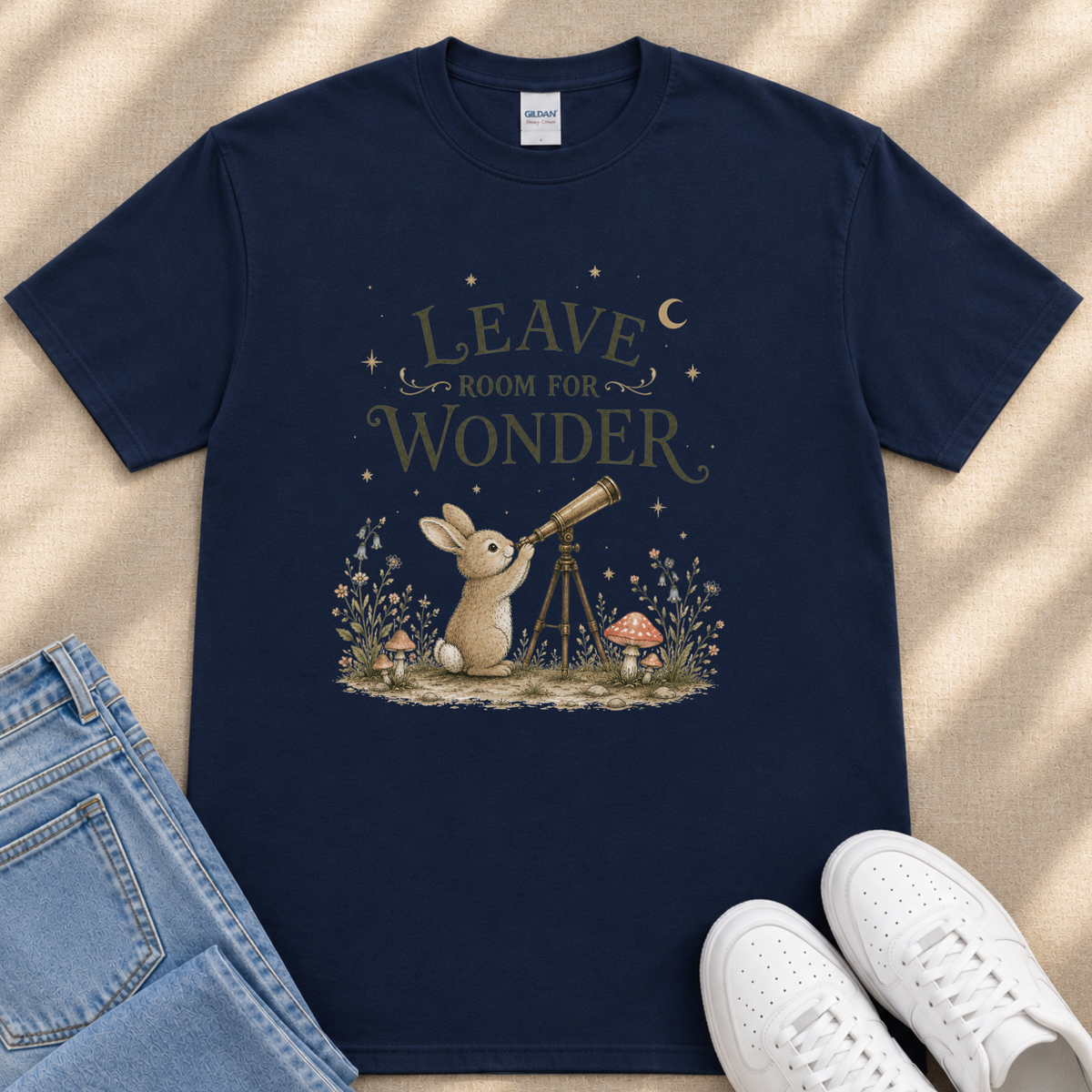 A navy blue t-shirt with a whimsical illustration of a rabbit gazing up at the night sky, accompanied by the text "LEAVE ROOM FOR WONDER".