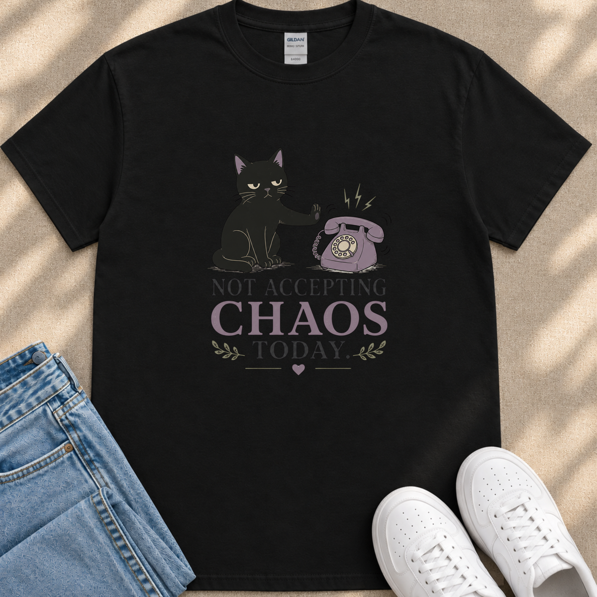 A black t-shirt with a graphic design depicting a cat and a telephone, along with the text "NOT ACCEPTING CHAOS TODAY" printed on it.
