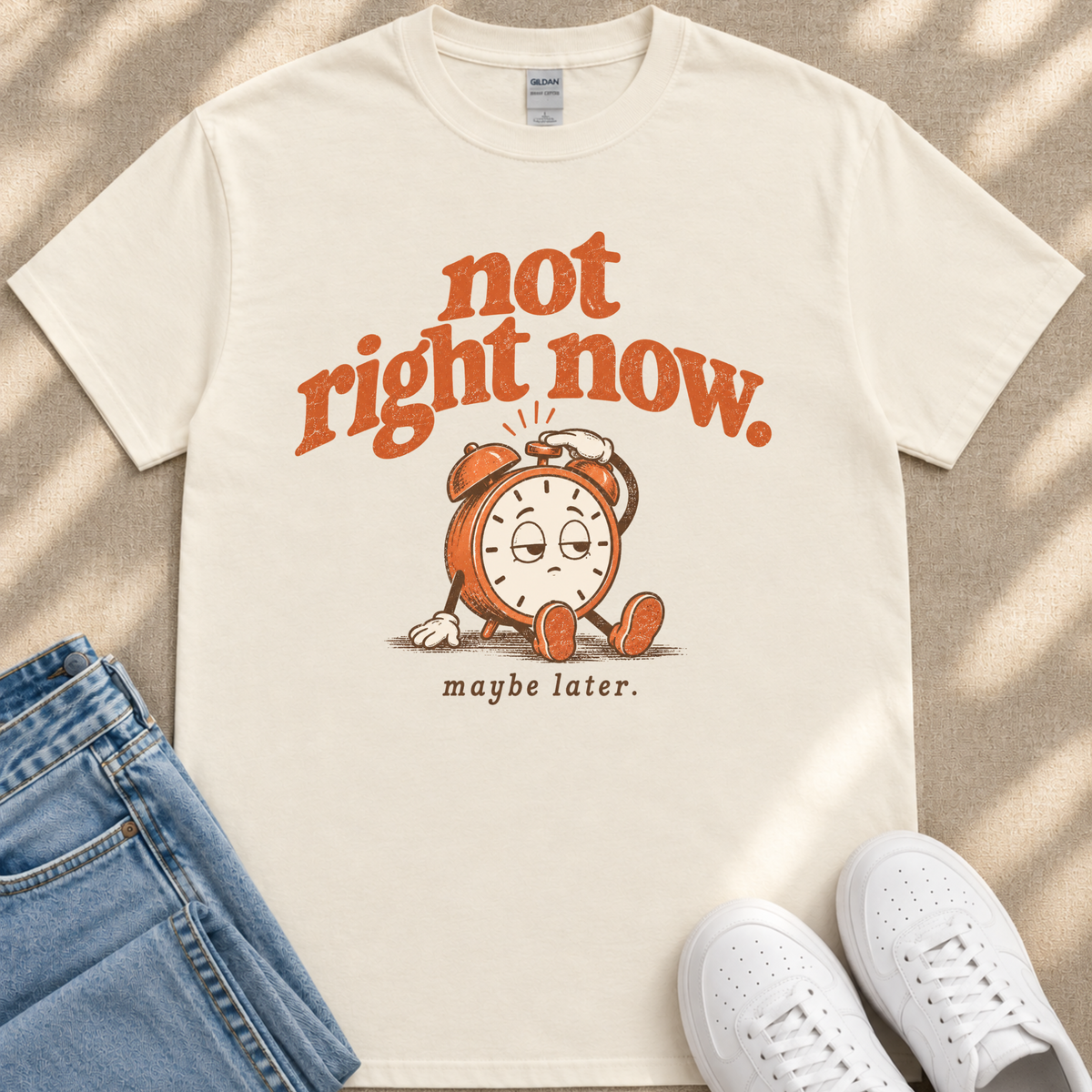 A white t-shirt with a graphic design of a clock and the text "not right now. maybe later."