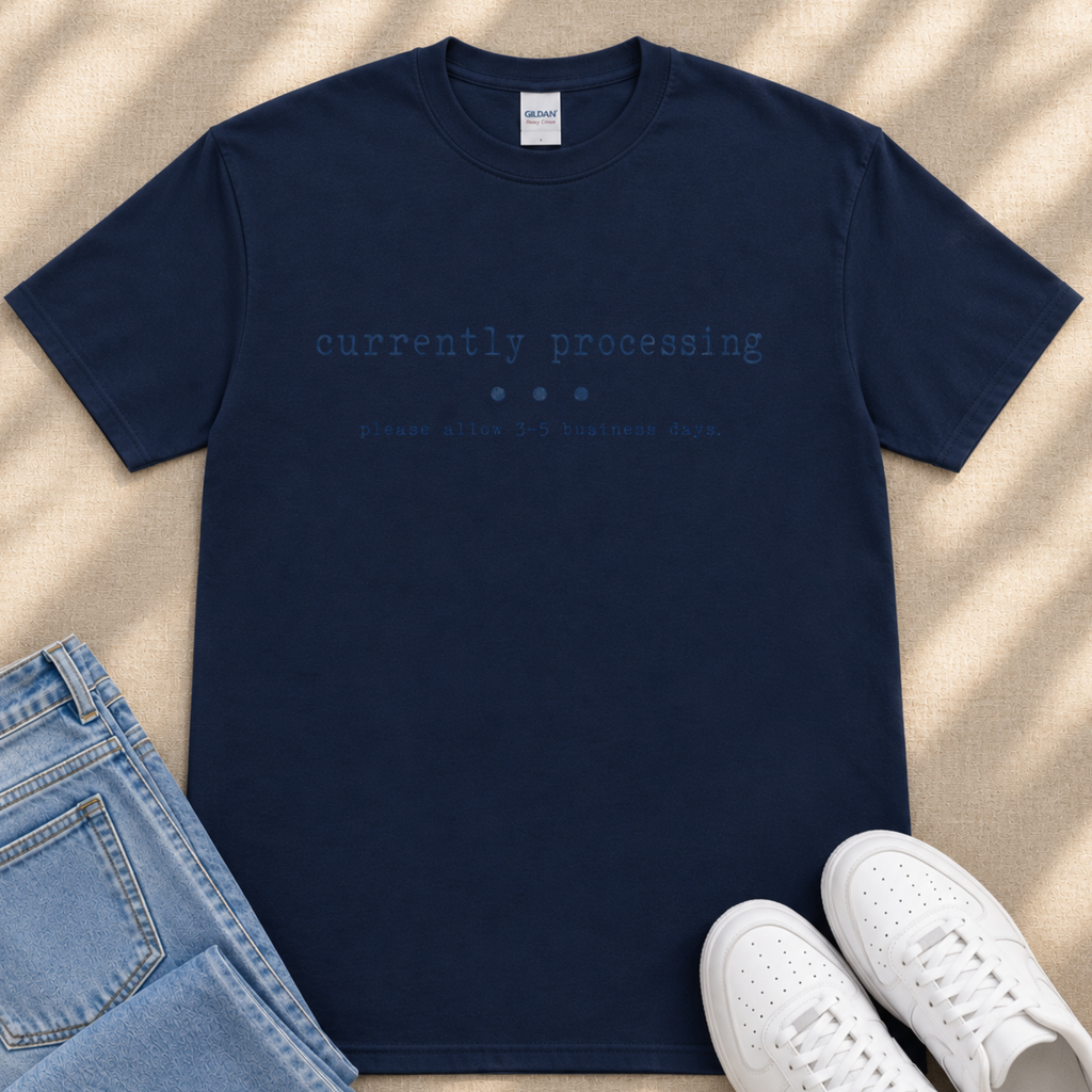 A navy blue t-shirt with the text "currently processing" printed on it, along with a pair of jeans and white sneakers.